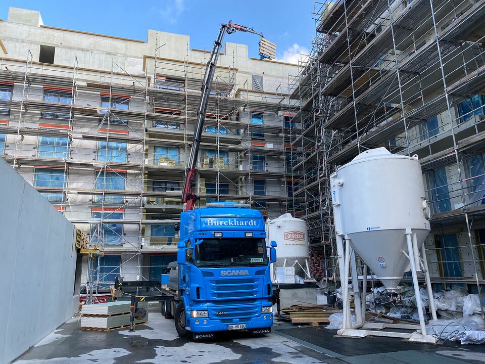 Ein Kran hebt Baumaterialien an einer Baustelle.