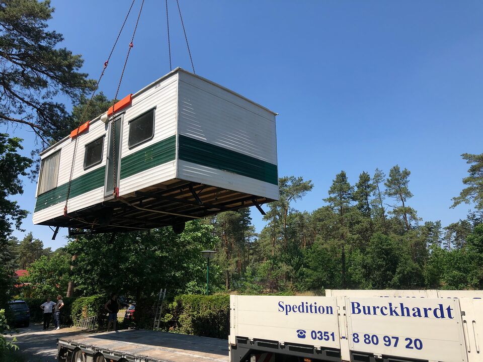 Ein Kran hebt ein Modulhaus an einen vorgesehenen Platz.