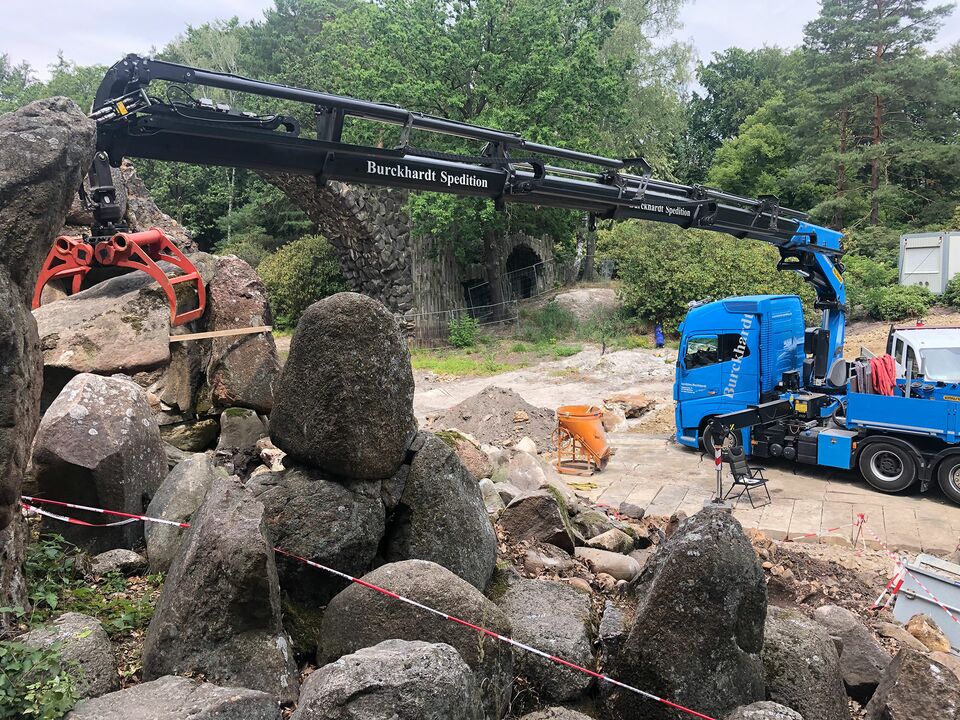 Ein Kran hebt Steine in einem Park.
