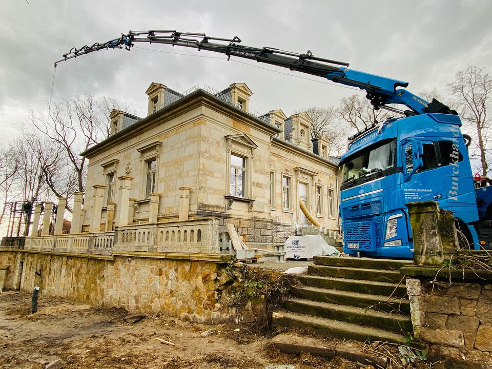 Ein Kran arbeitet an der Fassade eines historischen Gebäudes.