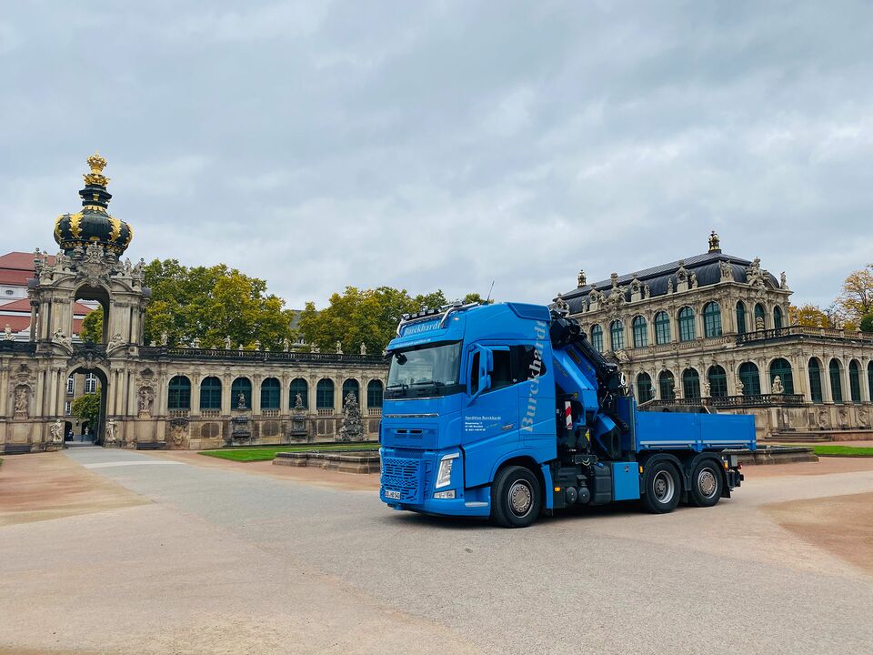 Ein blauer LKW steht vor der historischen Kulisse des Zwingers in Dresden, mit dem Kronentor und Barockarchitektur im Hintergrund.